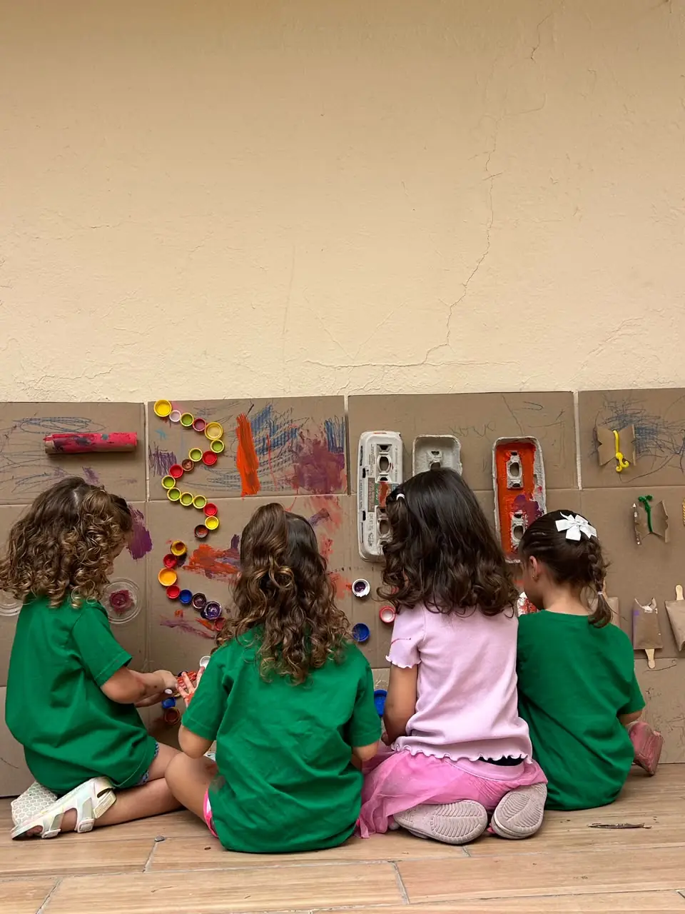 Niñas creando juntas en un mural de materiales reutilizados