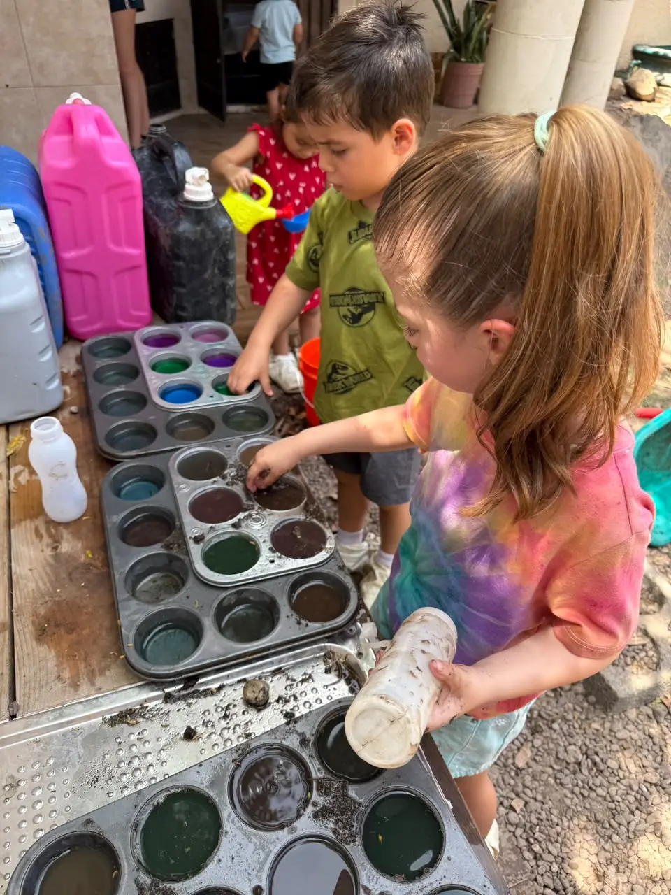 Niñas y niños jugando con agua y colores al aire libre