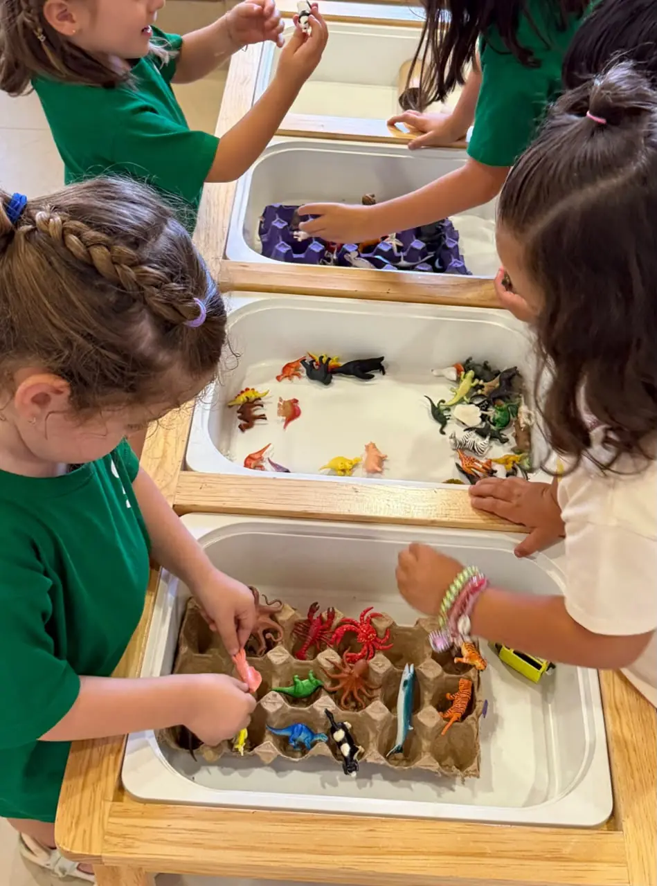 Niñas explorando materiales y figuras en una mesa sensorial