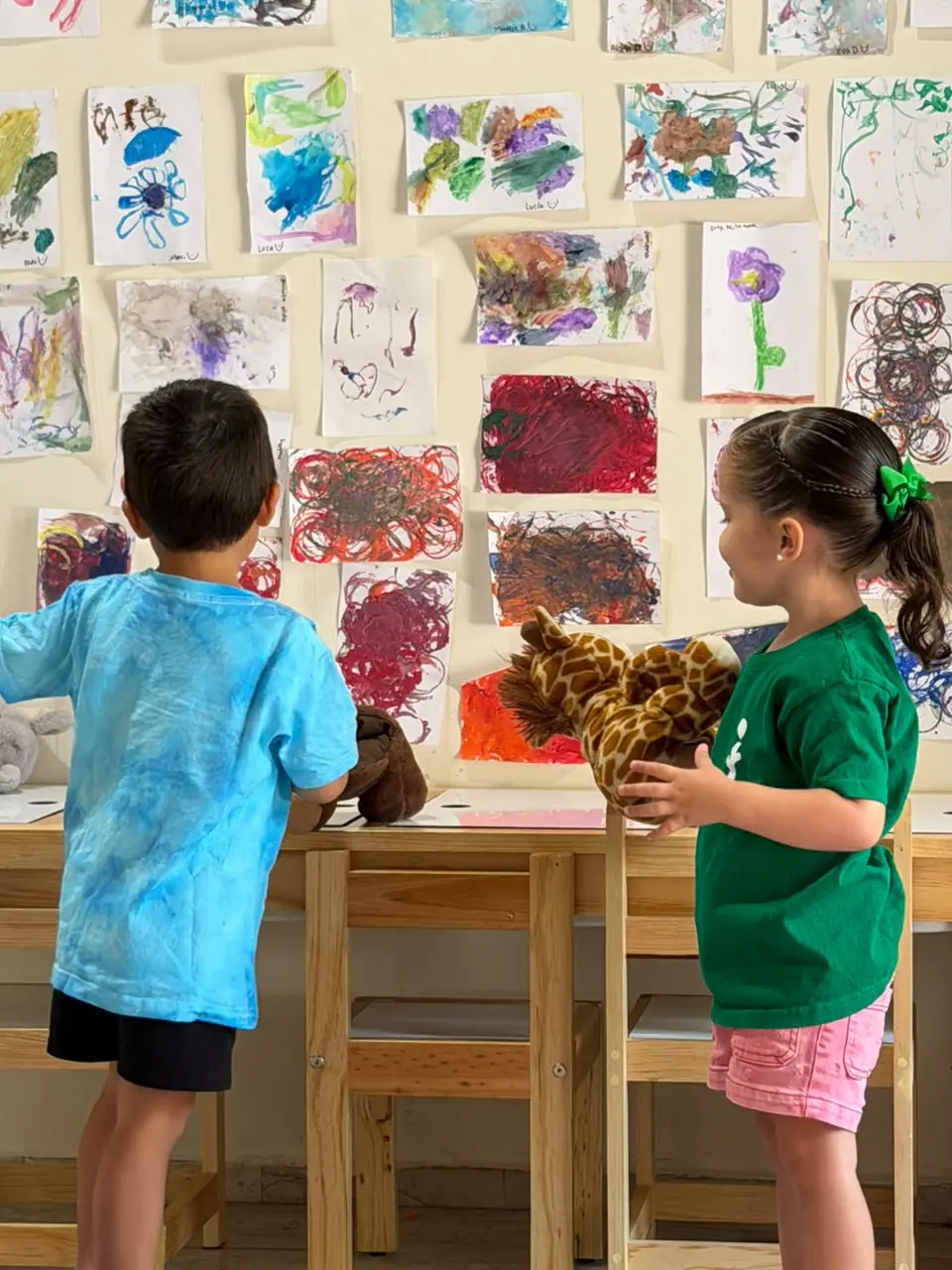 Niña y niño compartiendo sus creaciones frente a una galería de arte